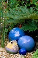 A salamander jug from Barcelona and cobalt blue balls in gravel in Robin Green and Ralph Cade's seaside style garden, London