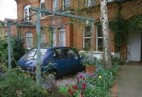 Front garden with Tulipa, forget-me-nots and car in carport   