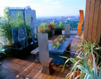 African themed roof terrace with Iroko decking, herringbone brick design panels.  Zinc-wrapped table, stainless steel throne chairs and core-ten steel shield sculpture