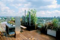 African themed roof terrace with over London - Water feature in black powder-coated container, iroko decking and five lead sculptures by Shaun Brosnan