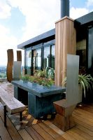 African themed roof terrace with sliding skylight, perimeter galvanised containers and iroko decking