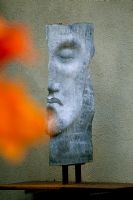 Lead sculpture head by Saun Brosnan seen through orange Cannas