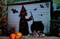 Halloween witch and couldron silhouette on blue shed cut from pvc pondliner, lit up at night