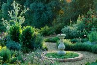 Sundial in centre of herb garden with Chamaemelum nobile, Allium schoenoprasum and Teucrium hamaedrys - Coton Manor, Northants