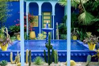 Cobalt blue fountain, cacti and yellow terracotta pots in the Moroccan style Yves St. Laurent Garden designed by Madison Cox, Chelsea 97