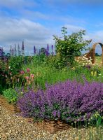 Raised willow beds and willow arch with cottage garden planting of Nepeta 'Walker's Low', Delphiums, Alliums, Persicaria bistorta 'Superba' and Leucanthemum vulgare