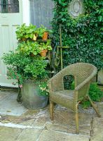 Lloyd Loom wicker chair by kitchen door with zinc dolly planter and old mangle used as a plant stand