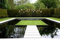Modern square pond with stepping stones and view to sculptures at Kiftsgate Court - Cotswolds