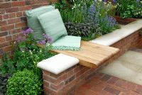 Built-in wooden seat in brick wall, raised beds with perennial planting in the Realistic Retreat garden, Chelsea 2007