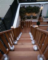 Modern roof garden with wooden steps, white walls and standard Photinias 