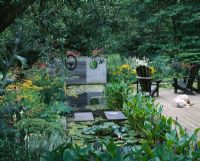Concrete sculpture over lily pond with dog, decking and adirondack chairs