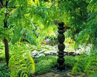 Totem sculpture of spherical forms beside pond