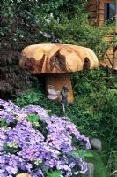 Large mushroom sculpted from wood and fairy amongst shrubs at Hampton Court FS 