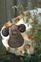 Stainless steel sheep ornament leaning against fence with bamboo