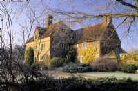 Frosty garden in winter with view of house - Coates Manor, Sussex 