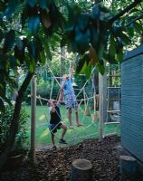 Spiders web rope climbing frame with young boys climbing on the web