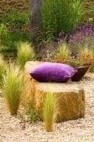 The gravel garden with rock seat, purple driftwood sculpture, Stipa tenuifolia, Trifolium rubens and copper container