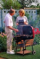 Man and woman cooking food on barbecue in garden - Reading 