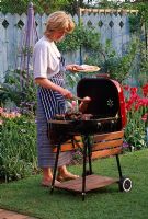 Woman cooking food on barbecue in the garden - Reading