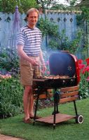 Man cooking food on barbecue in garden -  Reading