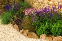 Gravel garden border with Astrantia 'Roma', Salvia caradonna, Aquilegia 'Ruby Port', box and Chionchloa rubra