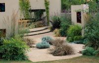 Dry garden with simple modern lines, stained glass windows and grasses growing in gravel in the CSMA garden at Hampton Court 