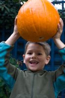 Young boy holding pumpkin high above head