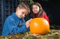 Young boy drawing a face on pumpkin