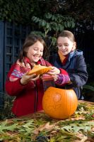Girls lifting lid of pumpkin, sequence of making Halloween lantern