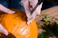 Cutting face with sharp knife from pumpkin, sequence of making Halloween lantern