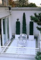 Contemporary stylish urban roof garden with metal table and chairs and topiary in containers - London  
