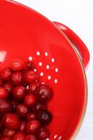 Cranberries in red colander on white linen