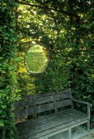 Round window in hedge above bench - Jardins du Prieure, Notre Dame d' Orsan, France