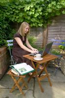 Lady working or relaxing in garden, with laptop