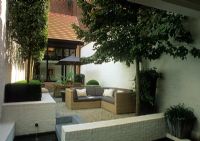 Modern courtyard town garden with white painted walls. Low retaining walls and furniture.