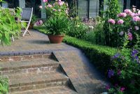 Shallow brick steps leading to patio with ramp on the side for wheel barrow access
