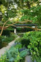 Cancer Research UK Garden Gold Medal winner with sculpture of three strands of continuous steamed oak above path. Planting of Cynara, Deschampsia cespitosa and  Salvia 'Mainacht'  - RHS Chelsea 2007 