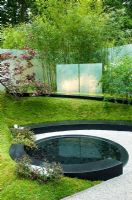 Pond in sloped garden with grass covered banks - 'Garden of Transience', Chelsea 2007