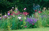 Armillary sphere in cottage style border early summer with Papaver, Gladiolus byzantinus and Geranium magnificum