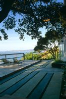 Contemporary concrete patio overlooking ocean. Parrallel lines planted with green plants - CA USA