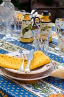 Mediterranean covered table with plates cutlery and glasses 

