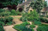 Gravel paths, steps and raised beds in herb garden in front of house - Hinton House, Bibury