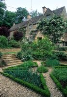 Gravel paths, steps and raised beds in herb garden in front of house - Hinton House, Bibury