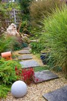 Stepping stone path through garden with Miscanthus 'Morning Light' and Imperata cylindrica 'Red Baron'