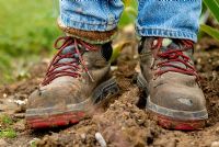 Well worn muddy work boots standing in garden soil