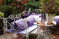 Decorative metal bench with purple cushions on patio