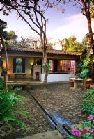 Brick cobblestone courtyard beside house with table, chairs and water rill - Malinalco, Mexico