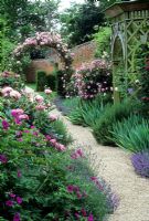 Walled garden with mixed borders of Paeonia, Lavandula, Iris and Geranium. Rosa arch and wooden gazebo - Seend Manor, Wiltshire 