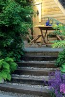 Sleeper steps with gravel treads leading to seating area with table and chairs.