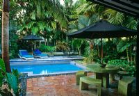 Courtyard walled garden with swimming pool, sun loungers, umbrellas, chairs and tables, and tropical planting - Key West, USA
